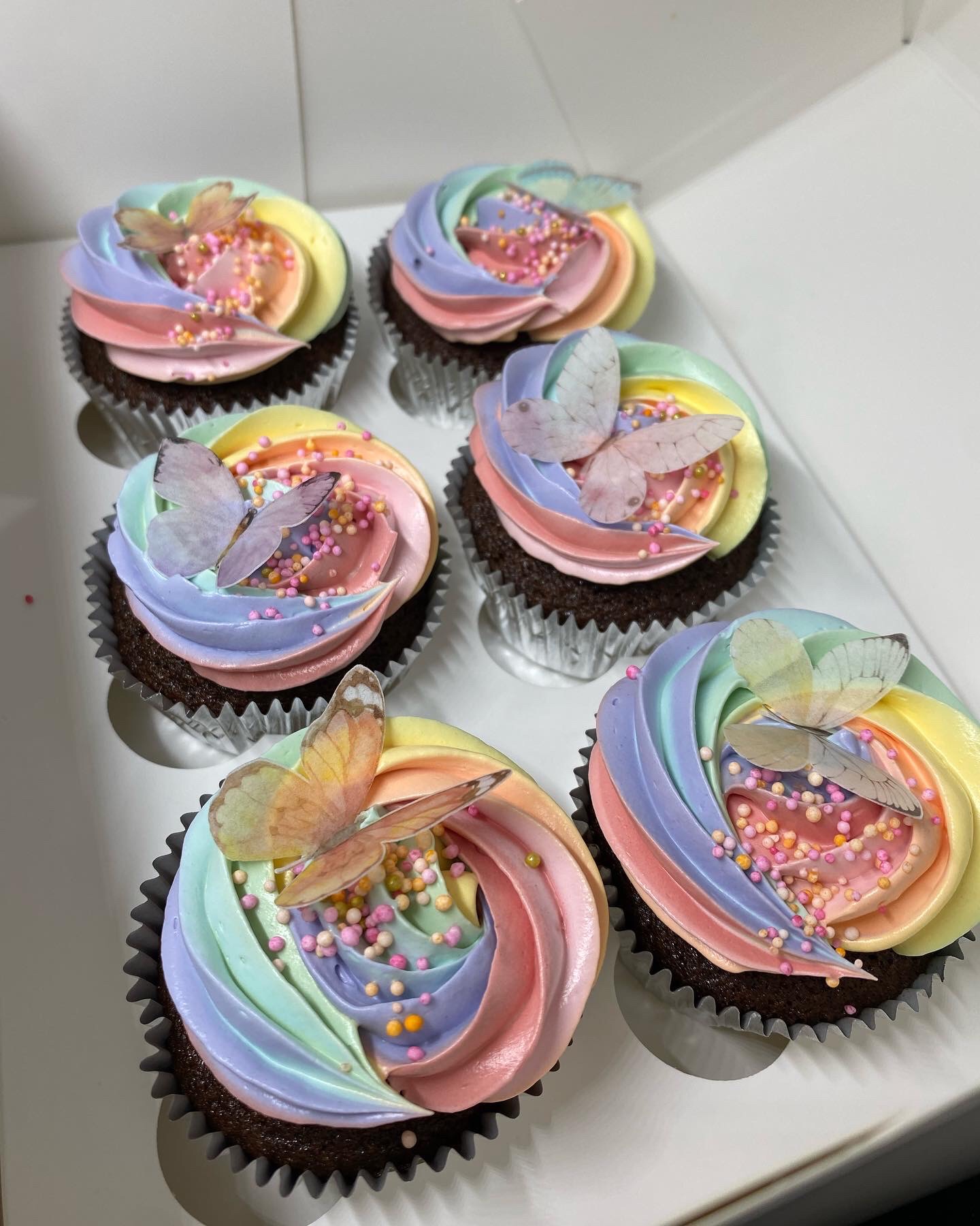 Pastel rainbow vanilla buttercream on a caramel filled chocolate cupcake