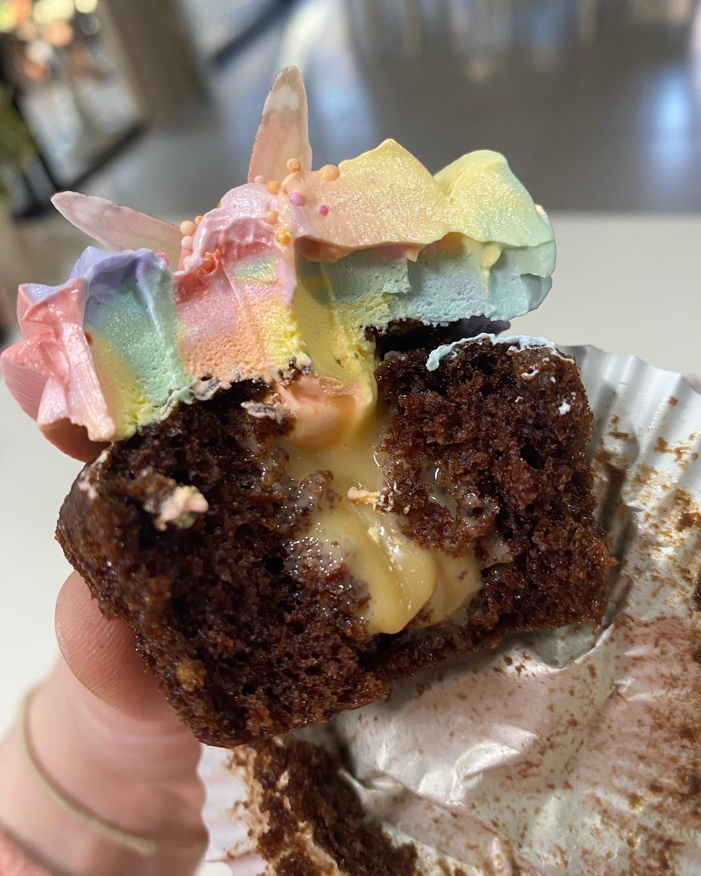 Pastel rainbow vanilla buttercream on a caramel filled chocolate cupcake